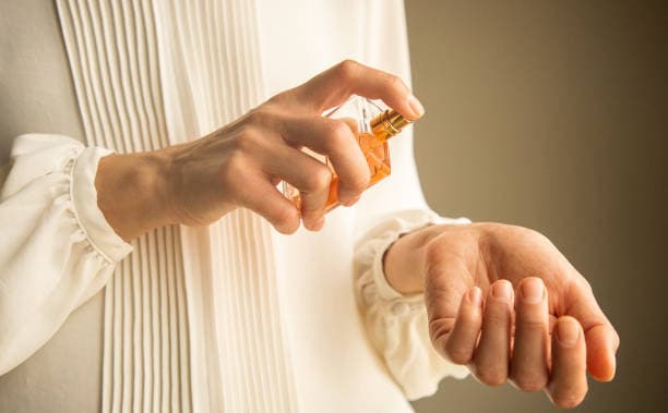 Close-up of someone testing perfume on their wrist in an elegant boutique setting